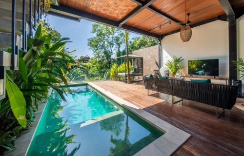 a swimming pool in a house with a wooden deck at Luxus Villa Jungle View 3br in Tumbak Bayuh