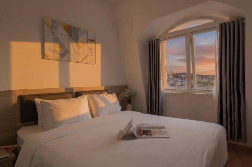une chambre avec un grand lit blanc avec une fenêtre dans l'établissement Bee Luxury Dalat Hotel, à Đà Lạt