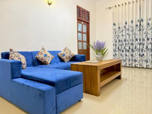 a blue couch in a living room with a table at Sasmika Villa Surf and Yoga Hostel in Weligama