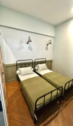 two beds in a room with two lamps on the wall at Dirumahbandung in Sarireja