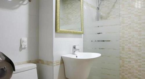 a white bathroom with a sink and a shower at Ewha Hotel in Jeju