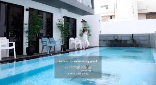 Una mujer está de pie junto a una piscina. en Capsule@Hive Bugis, en Singapur