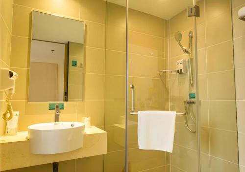 a bathroom with a shower and a sink and a mirror at City Comfort Inn Xianning Xian'an in Guanbuqiao