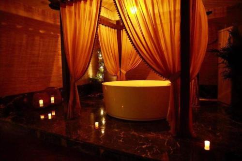 une salle de bain avec une baignoire sur un comptoir avec des rideaux dans l'établissement Weida Hotel Jinhua, à Jinhua