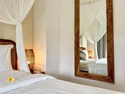a bedroom with two beds and a mirror at Hot Stone Club Ubud in Ubud