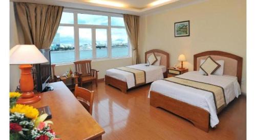 a hotel room with two beds and a table at Bamboo Green Hotel in Da Nang