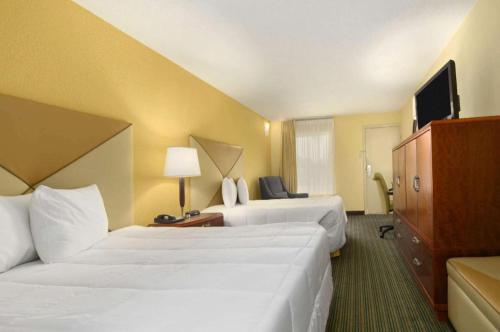 a hotel room with two beds and a television at Days Inn by Wyndham Brunswick/St. Simons Area in Glynn Heights