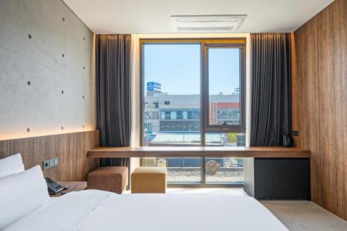 a hotel room with a bed and a large window at 대구 동성로 호텔 에이유 in Hyomoktong-Ilgu