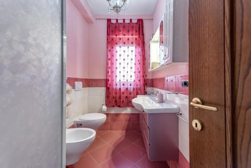 a pink bathroom with two toilets and a sink at Sandra House - Certaldo in Certaldo