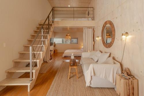 Sinŏm-niにあるJeju Mooi Pensionのリビングルーム(白いソファ、階段付)