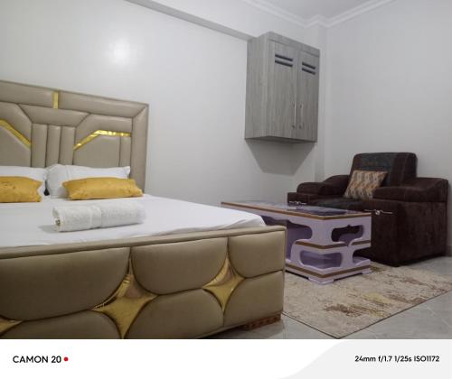 une chambre avec un grand lit et une chaise dans l'établissement Prift Royal Apartments, à Meru