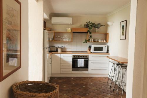 a small kitchen with white cabinets and a microwave at Dennis Cottage Clare Valley in Auburn