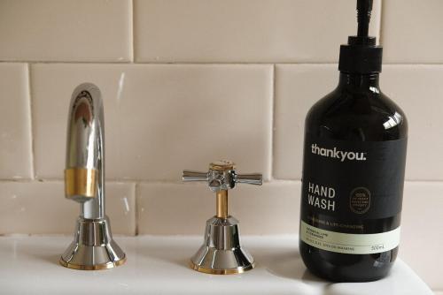 a bottle of wine sitting on a sink next to a faucet at Dennis Cottage Clare Valley in Auburn