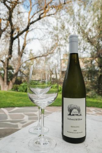 a bottle of wine sitting next to a wine glass at Wild Olive Cottage Clare Valley in Auburn