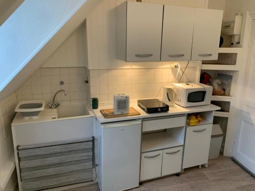 a small kitchen with white cabinets and a microwave at 45 Grande Rue bis in Ault