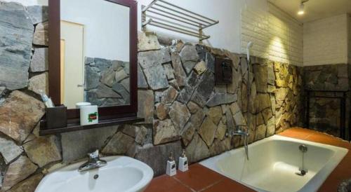 a bathroom with a sink and a tub and a mirror at Gecko Hotel in Hanoi