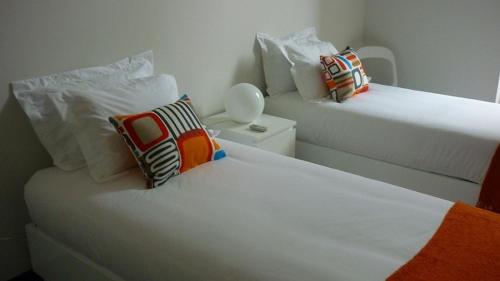 a hotel room with two beds and a white comforter at 12 Short Term in Porto