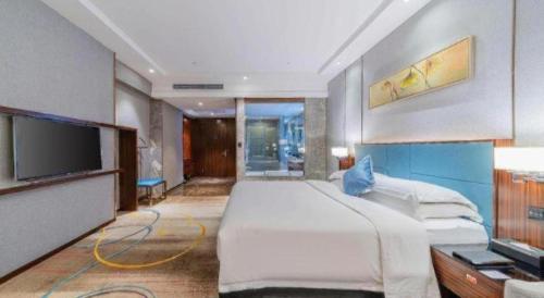 a bedroom with a large bed and a flat screen tv at Ramada Foshan Shunde in Shunde