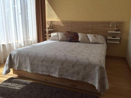 una camera da letto con un grande letto con lenzuola e cuscini bianchi di Saulės Sonata Etude a Druskininkai