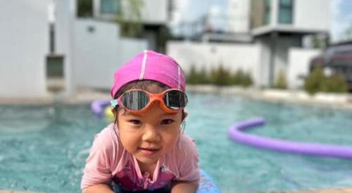 une petite fille portant des lunettes de soleil au bord d'une piscine dans l'établissement My Room by Sermsub, à Aranyaprathet