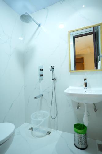 ein weißes Badezimmer mit Waschbecken und Spiegel in der Unterkunft Purple orchid in Bangalore