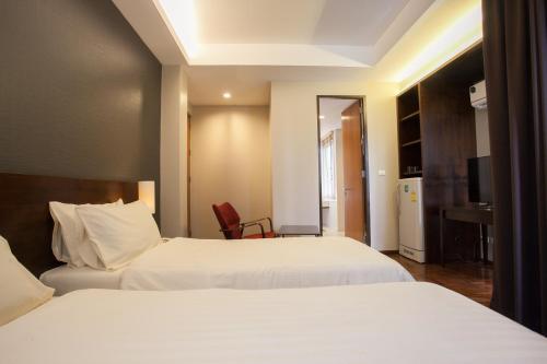 a hotel room with two beds and a desk at Baansilom Soi 3 in Bangkok