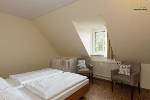 a bed in a room with two chairs and a window at Boddenhof Apartment 56 - 2 SZ, freundlich, modern in Buschvitz