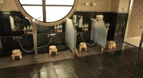 a bathroom with two shower stalls and a mirror at Hotel Saiyou WAKIGAWA in Hirado