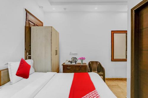 a bedroom with a white bed with a red blanket at Hotel O JANGPURA INN in New Delhi