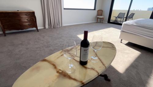 un tavolo di vetro con una bottiglia di vino e bicchieri da vino di Beach House Perth a Perth