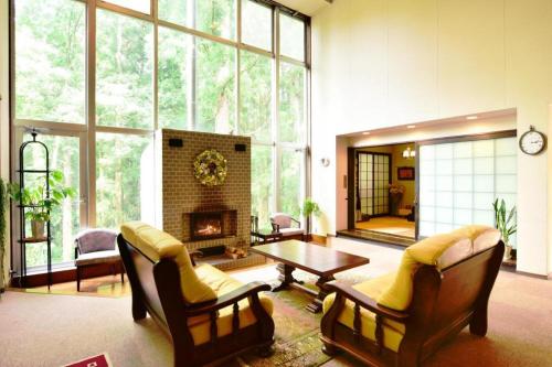 a living room with a fireplace and a table and chairs at HAKUBA Moegi HOTEL in Hakuba