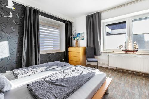 a bedroom with a bed and a chair and a window at Deichperle Friedrichskoog Spitze in Friedrichskoog
