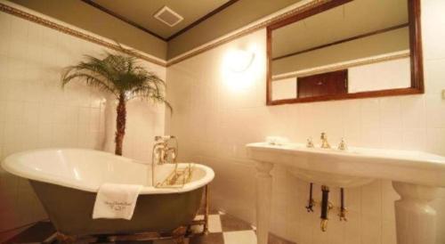 a bathroom with a bathtub and a sink and a bath at Unzen Kanko Hotel in Unzen