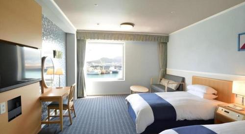 une chambre d'hôtel avec deux lits, un bureau et une fenêtre dans l'établissement Green Hill Hotel Onomichi, à Kaneyoshi