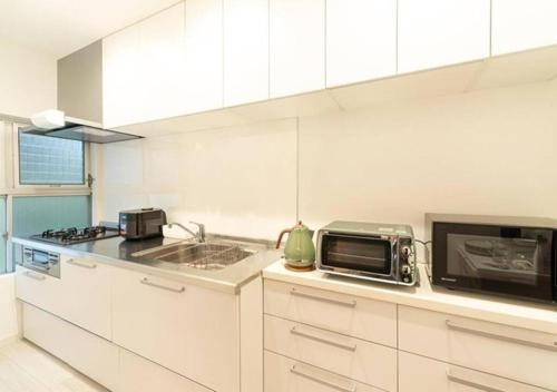 a white kitchen with a microwave and a sink at TenangTenang - Izu Oceanic Villa in Ito