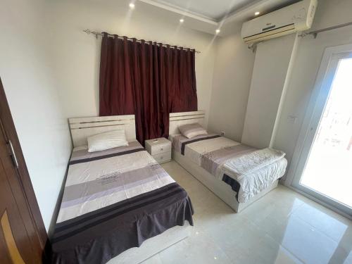 zwei Betten in einem kleinen Zimmer mit Fenster in der Unterkunft Marvel lotus in Hurghada