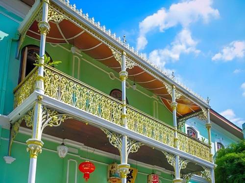 a green building with a gold railing on a balcony at Power Hotel in Kampong Sungai Gelugor