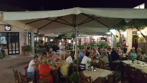 a group of people sitting at tables under an umbrella at Chariandry Court in Pissouri