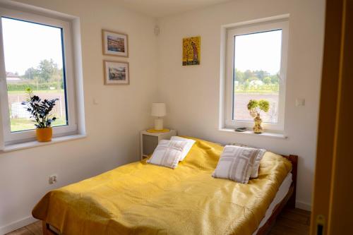 a bedroom with a bed with two pillows and two windows at Radawnica pl - Tu odpoczniesz! in Skorka