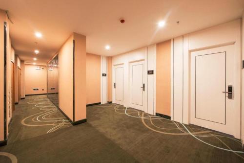 a hallway with white doors and wires on the floor at Xana Lite Beijing West Station Branch in Beijing