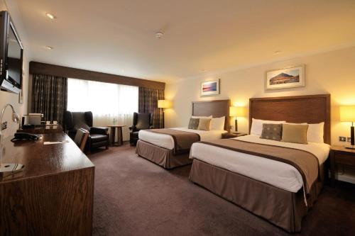 a hotel room with two beds and a desk at The Aberdeen Altens Hotel in Aberdeen