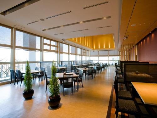 a dining room with tables and chairs and windows at Gamagori Onsenkyo Mikawa Bay Hills Hotel in Nishio