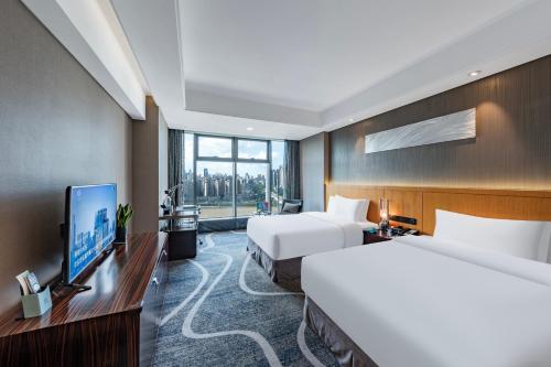 a hotel room with two beds and a flat screen tv at C Plaza Hotel in Chongqing