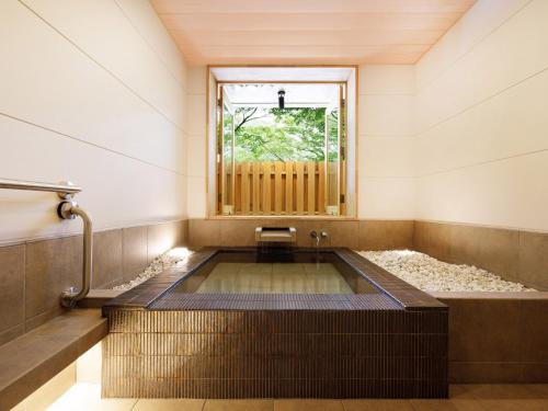 a bath tub with a window in a room at Yubaraonsen Yubaranoyado Komeya in Maniwa