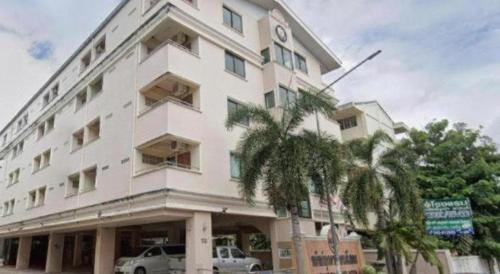 un bâtiment blanc avec des palmiers devant dans l'établissement Submukda Grand Hotel, à Mukdahan