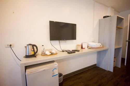 a room with a desk with a television on a wall at Baan Khun Nine in Ratchaburi