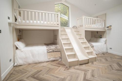 two white bunk beds in a room with wooden floors at Luxury cottage with high-end bathrooms - NEWLY REFURBISHED in Sutton Scotney
