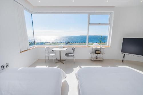Cette chambre blanche dispose de 2 lits et d'une grande fenêtre. dans l'établissement Oceanview,Villa de 427, à Seogwipo