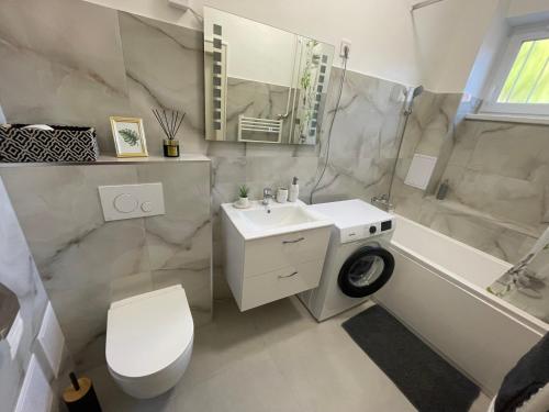a bathroom with a sink and a toilet and a tub at Magnolia Apartman in Győr