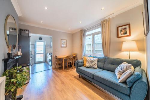 a living room with a blue couch and a table at Entire Modern Apartment with Garden Near Underground Station in London